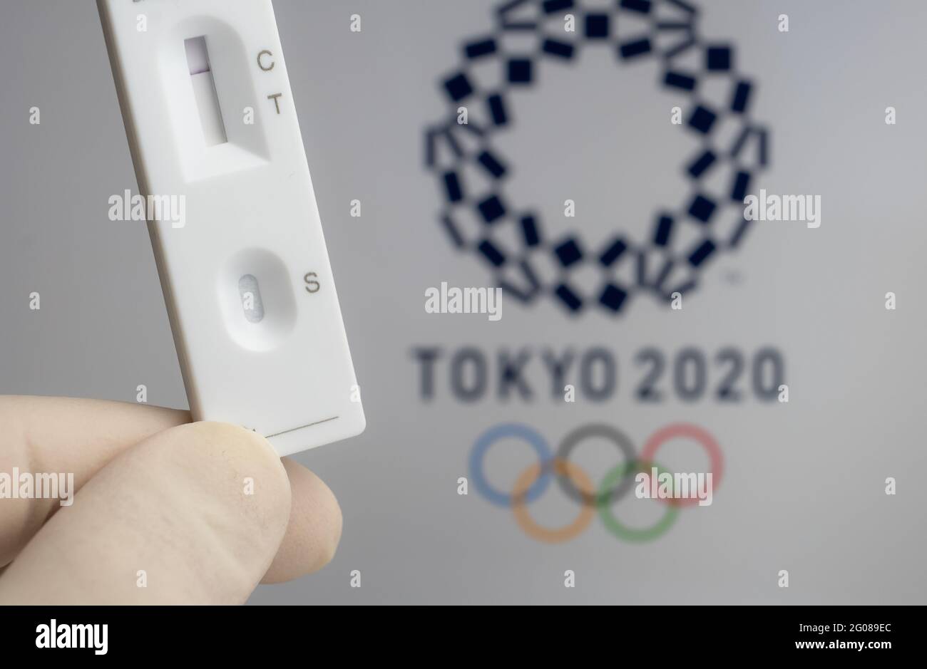 Test PCR négatif à l'avant et logo Tokyo 2020 flou sur fond flou. Concept pour les Jeux Olympiques de Tokyo COVID en 2021. Stafford, United King Banque D'Images