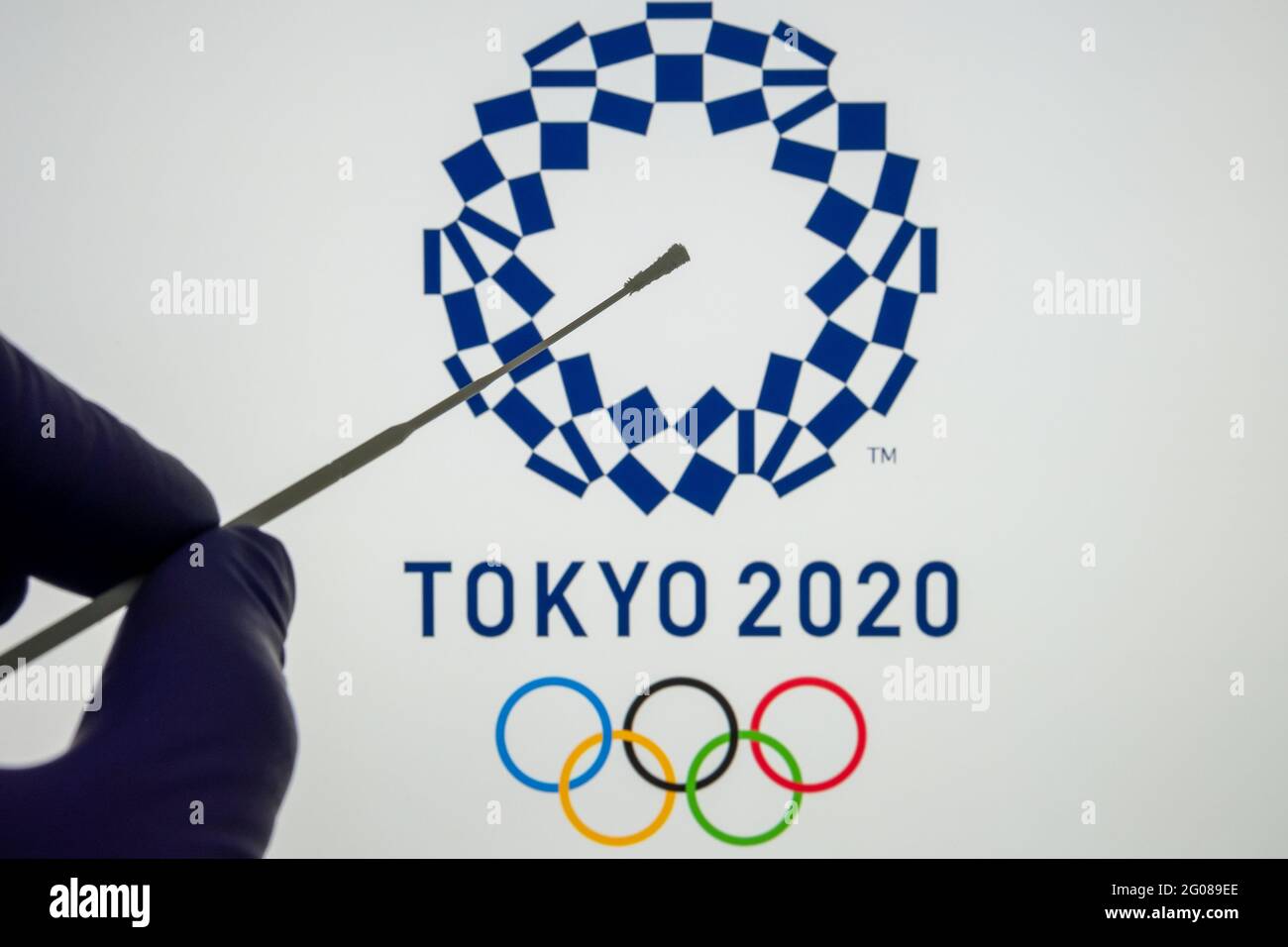 Test PCR négatif à l'avant et logo Tokyo 2020 flou sur fond flou. Concept pour les Jeux Olympiques de Tokyo COVID en 2021. Stafford, United King Banque D'Images