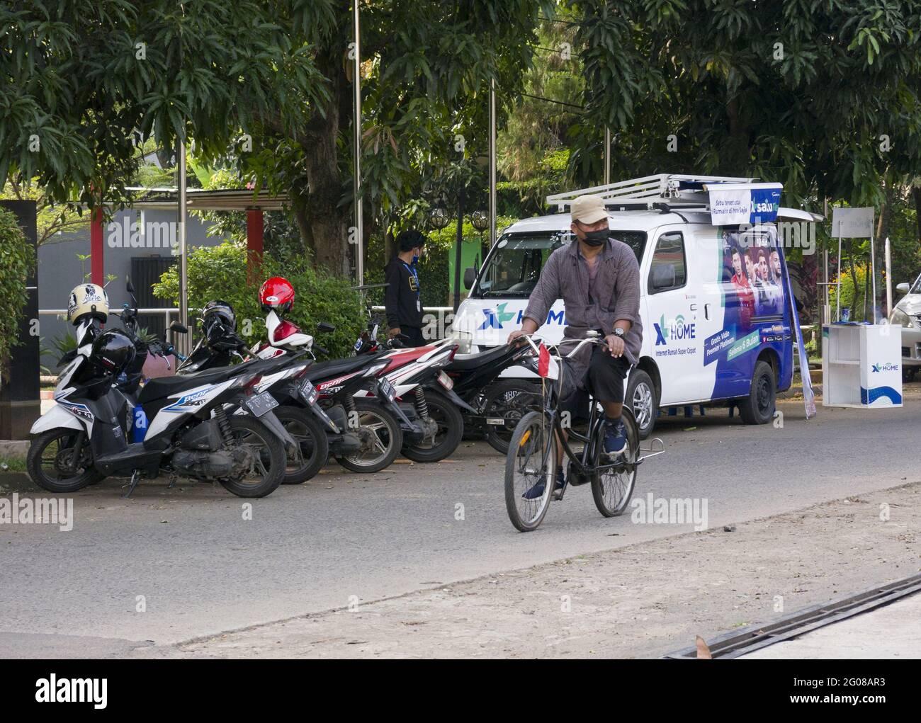 Jakarta, Indonésie - 1er juin 2021 : le cycliste portant un masque conduit sur la route avec des vélos et des voitures de stationnement comme toile de fond, usage éditorial seulement Banque D'Images