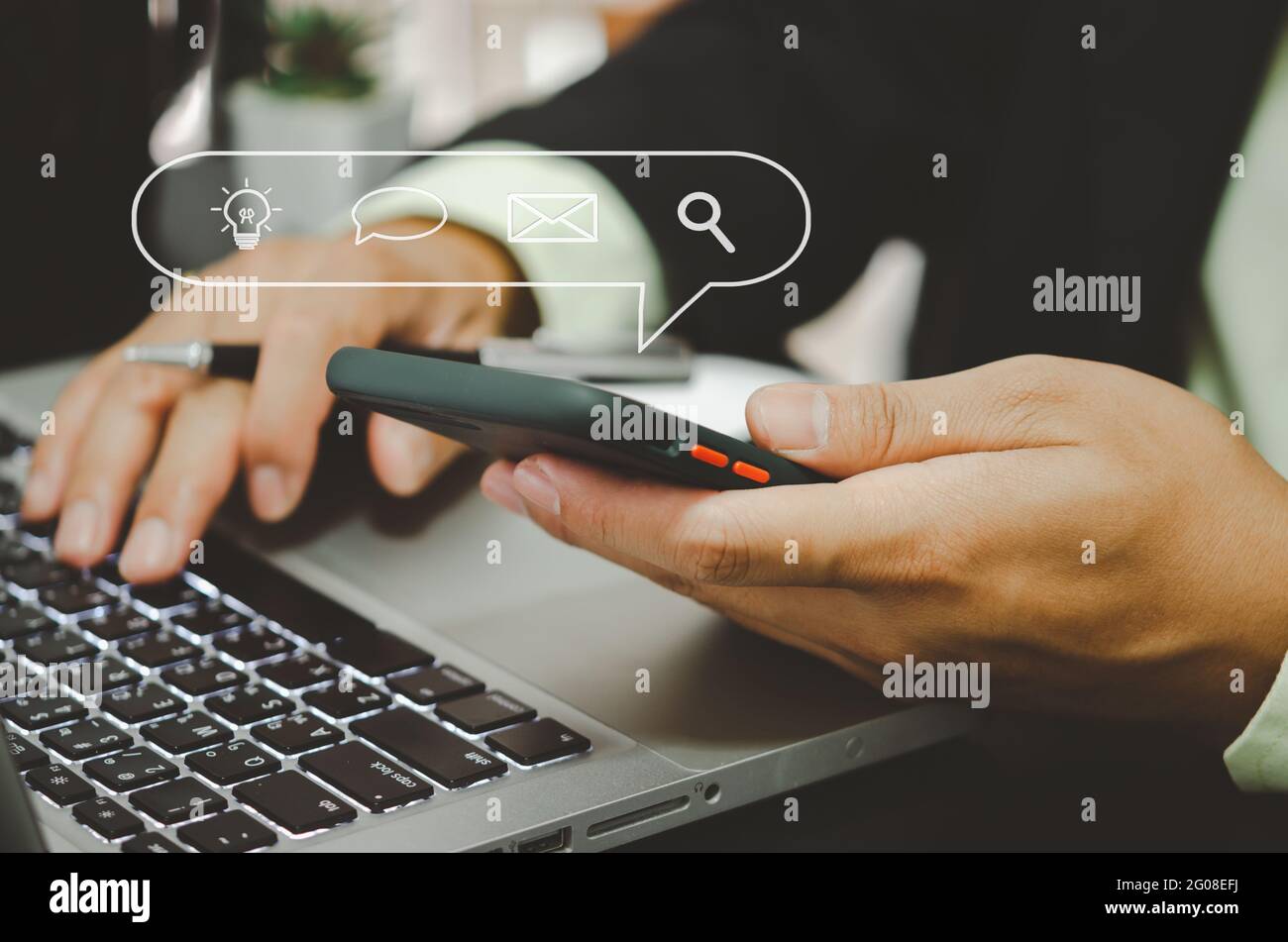 Homme d'affaires main tenant une icône de téléphone mobile mail chat recherche et médias sociaux et réseaux. Banque D'Images