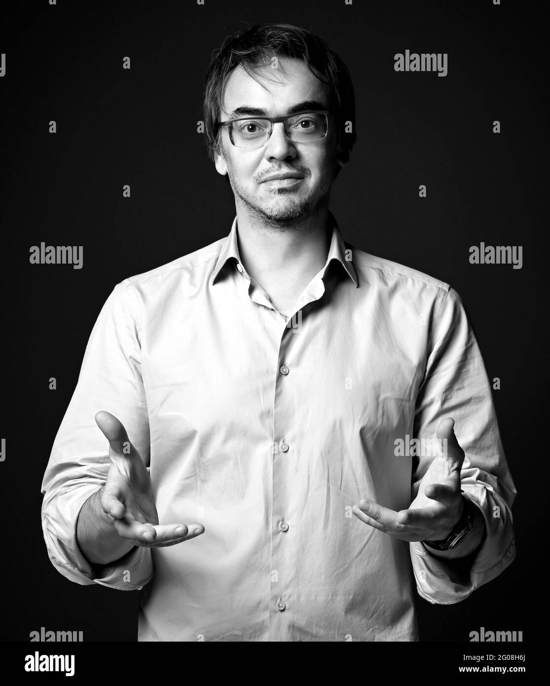 Portrait noir et blanc d'un homme d'âge moyen non rasé dans une chemise tenant les mains vers nous, paumes vers le haut Banque D'Images