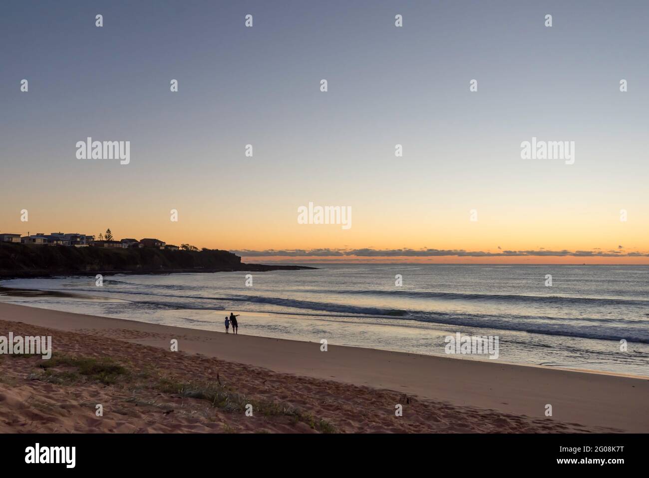 Un père et un fils silhouettés pointant vers l'océan juste avant le lever du soleil à Culburra Beach (sud) sur la côte sud de la Nouvelle-Galles du Sud de l'Australie Banque D'Images