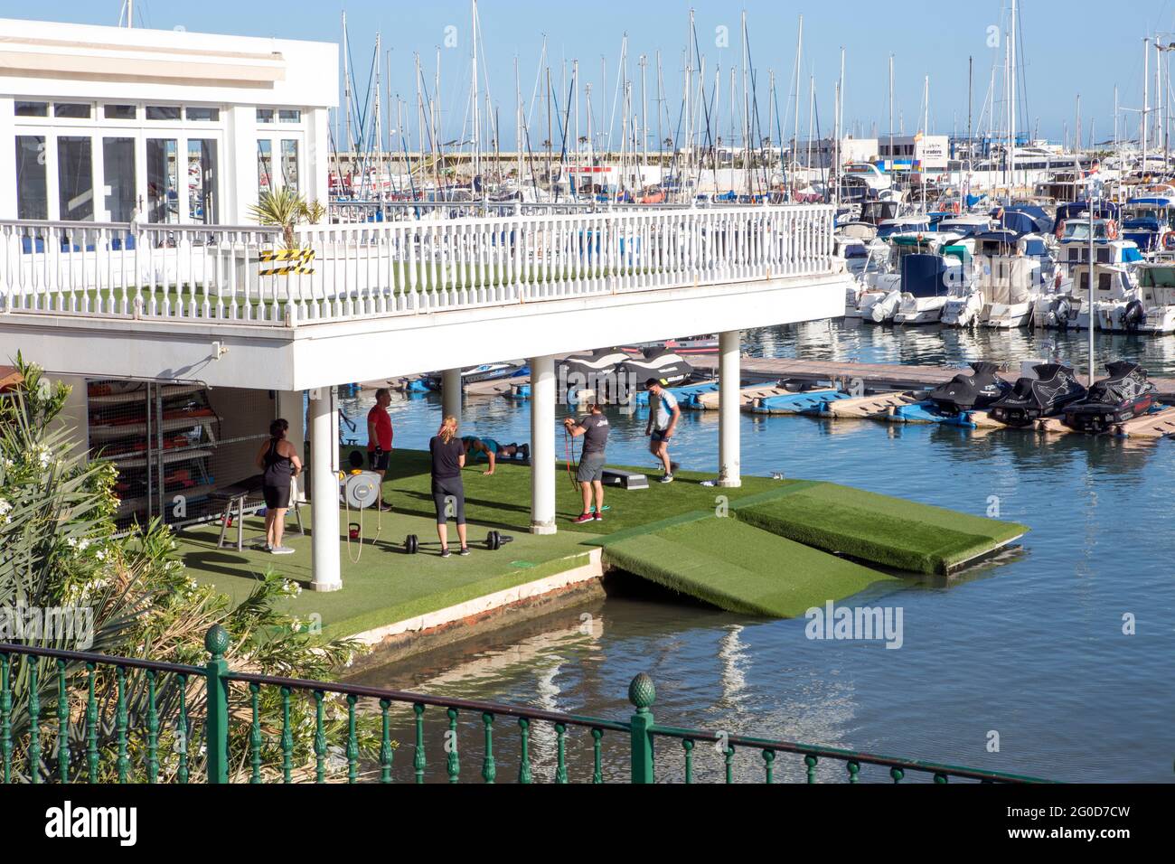 Les personnes s'exerçant dans une salle de gym située sur la terrasse de la maison sur l'eau de mer dans le port à côté des bateaux amarrés.Torrevieja, Alicante, Espagne. 05-1 Banque D'Images