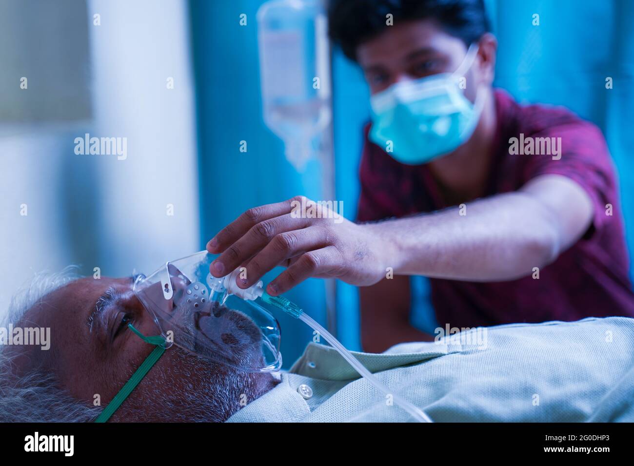 Fils avec masque médical prenant soin de vieux père malade à l'hôpital en vérifiant masque d'oxygène de ventilateur - concept de personnes âgées santé parentale Banque D'Images