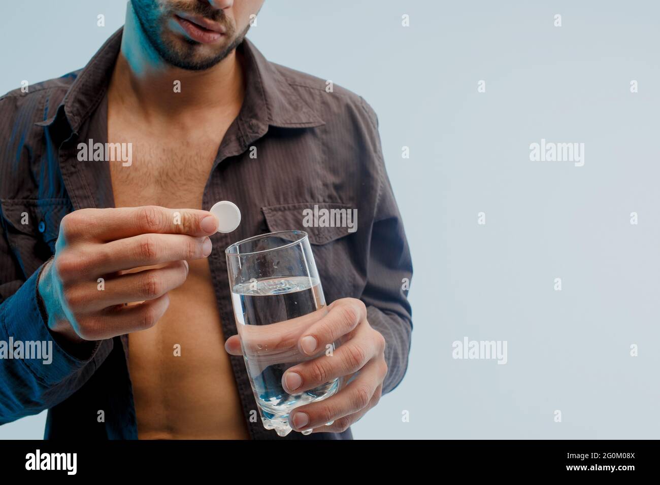 Homme jeter la pilule dans le verre avec de l'eau, gros plan Banque D'Images