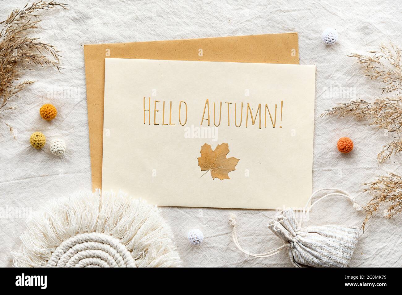 Texte Hello Autumn sur carte blanche avec enveloppe. Hors blanc textile plat avec macrame et roseaux secs, pampas herbe. Sac Franrance à l'automne naturel Banque D'Images
