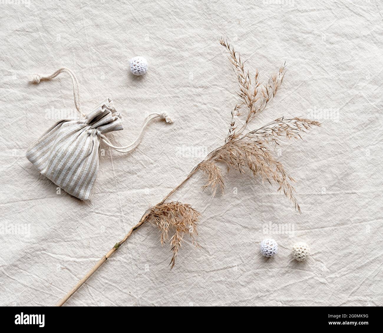 Toile à plat avec roseaux secs, pampas d'herbe et sac en coton avec herbes parfumées sèches. Fond de nappe blanc cassé avec coton tricoté fait à la main Banque D'Images