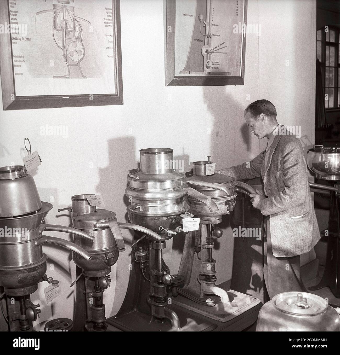 Histoire des machines de fabrication de lait et de crème. Un homme dans un musée de séparateurs. Machines destinées à séparer la crème et le lait écrémé du lait frais. Ce faisant, il a été possible de transformer la crème en beurre et en fromage à petite échelle. Ces séparateurs ont été introduits à la fin des années 1800. Suède 1953 réf. BM26-4 Banque D'Images