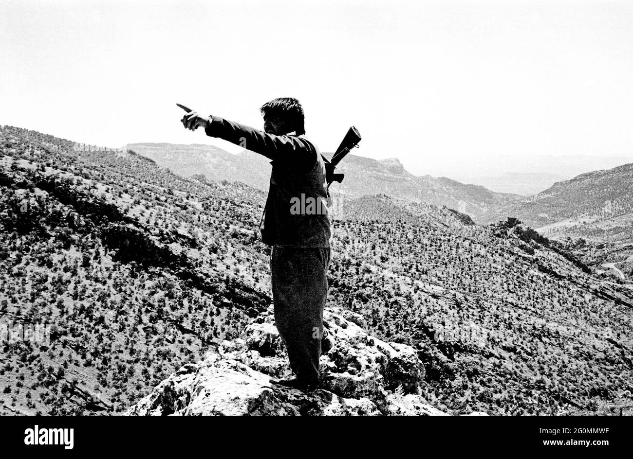 Nord de l'Irak, frontière avec la Turquie, Kurdistan. Juillet 1992. Un combattant du Parti des travailleurs du Kurdistan - PKK - regarde sur le terrain montagneux de la région pour laquelle il et ses compatriotes luttent pour l'autonomie. Banque D'Images