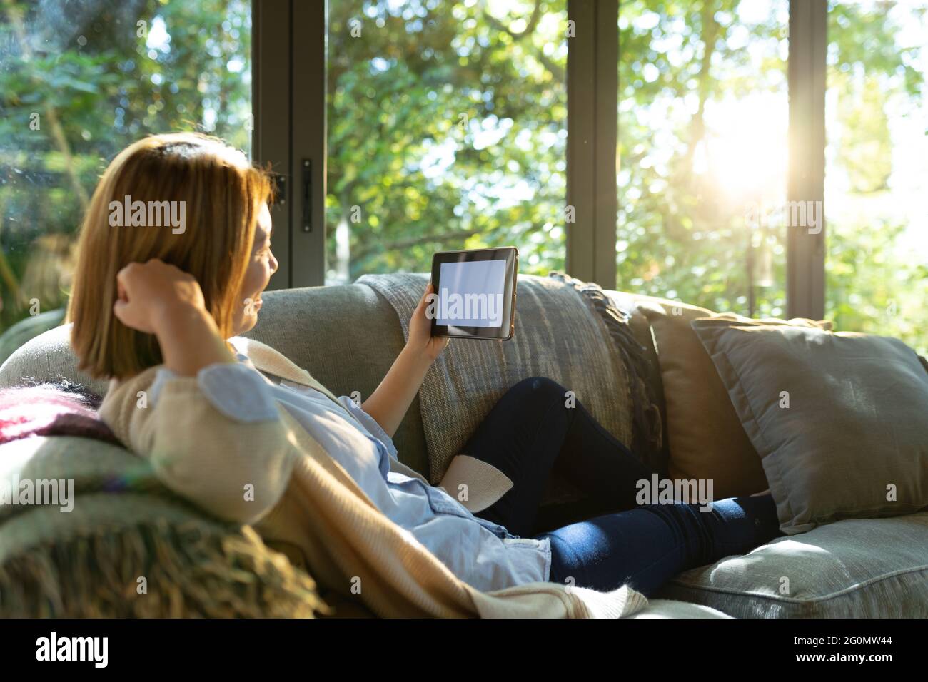 Femme asiatique discutant avec une tablette à écran vierge, assise sur un canapé à la maison Banque D'Images
