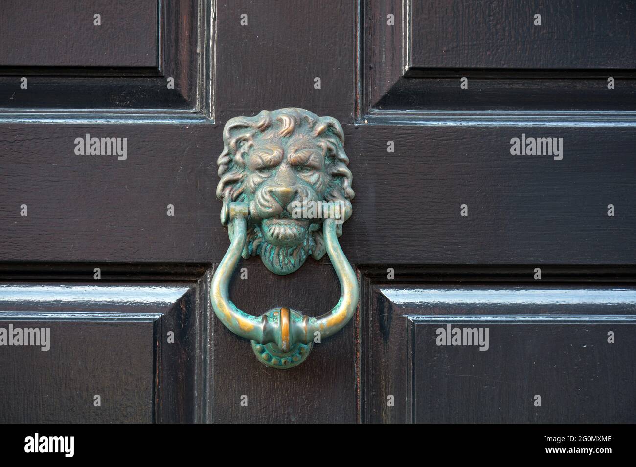 Des lions anciens et abîmés sont à la tête d'une porte en bois sombre. Banque D'Images