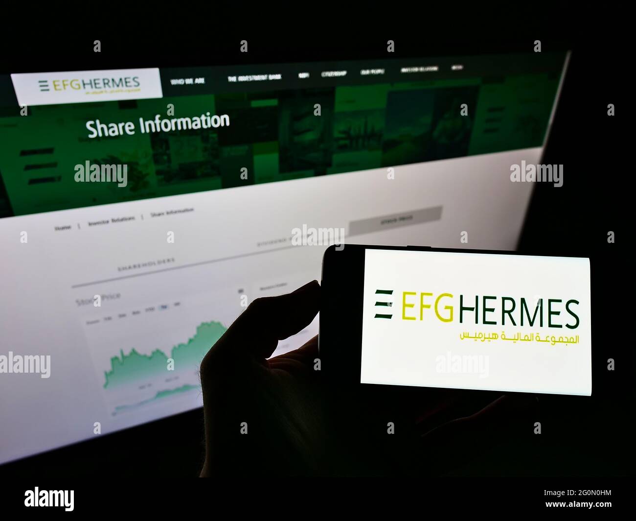 Personne tenant un smartphone avec le logo de la société financière égyptienne EFG Hermes Holding S.A.E. à l'écran devant le site Web. Mise au point sur l'affichage du téléphone. Banque D'Images