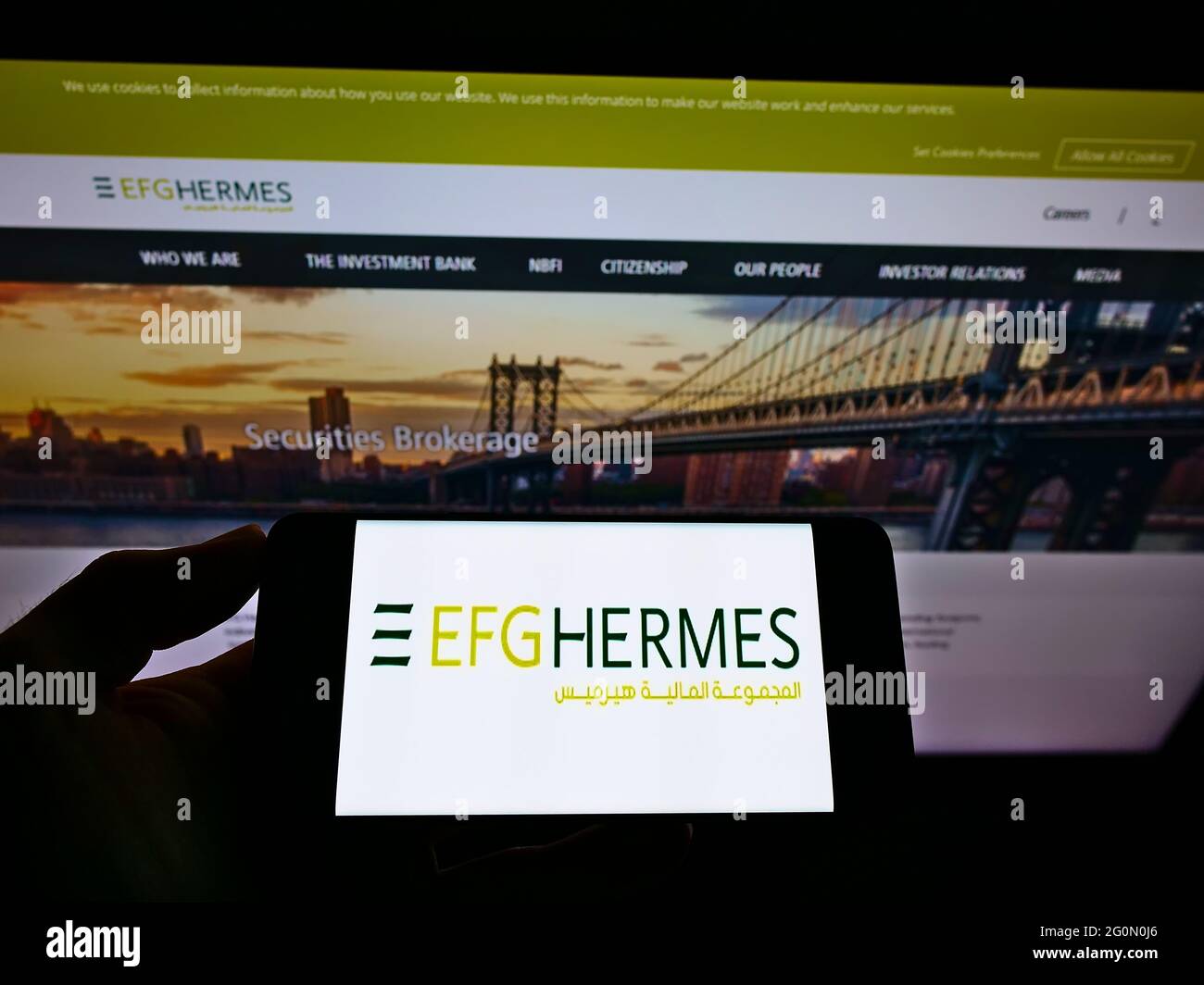 Personne tenant un téléphone portable avec le logo de la société financière égyptienne EFG Hermes tenant SAE sur l'écran en face de la page web. Mise au point sur l'affichage du téléphone. Banque D'Images