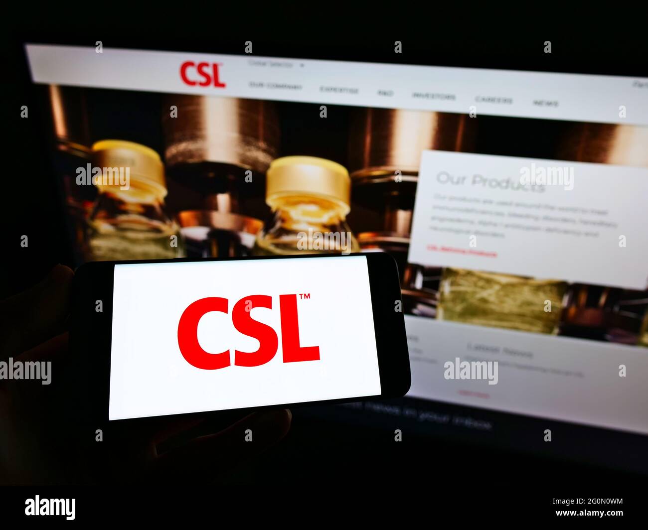 Personne tenant un téléphone portable avec le logo de la société australienne de produits pharmaceutiques CSL Limited à l'écran en face de la page Web d'affaires. Mise au point sur l'affichage du téléphone. Banque D'Images