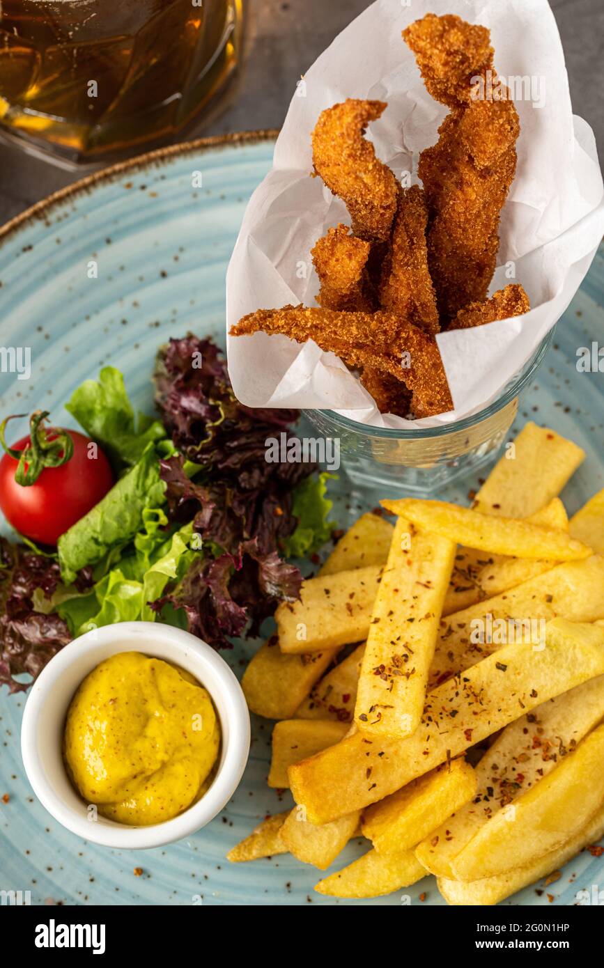 Poulet frits et frites sur une assiette bleue avec bière Banque D'Images