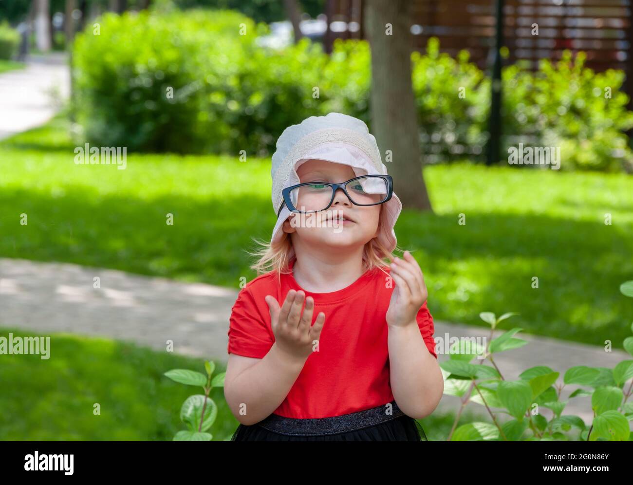 Portrait extérieur d'une petite fille de 2,5 ans portant des lunettes. Drôle et jolie fille dans le parc. Banque D'Images