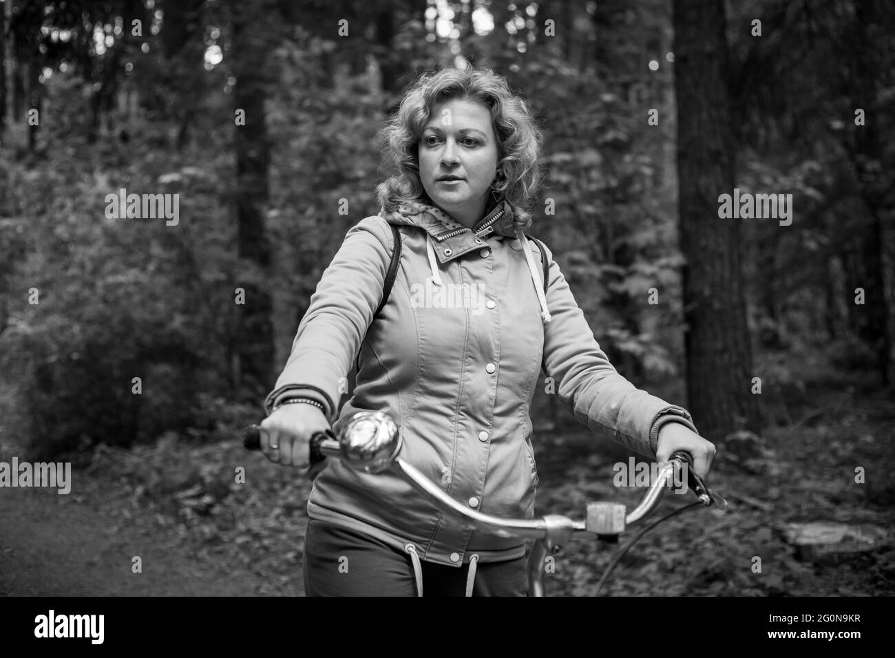 Femme blonde avec vélo dans les bois. Photo en noir et blanc. Banque D'Images