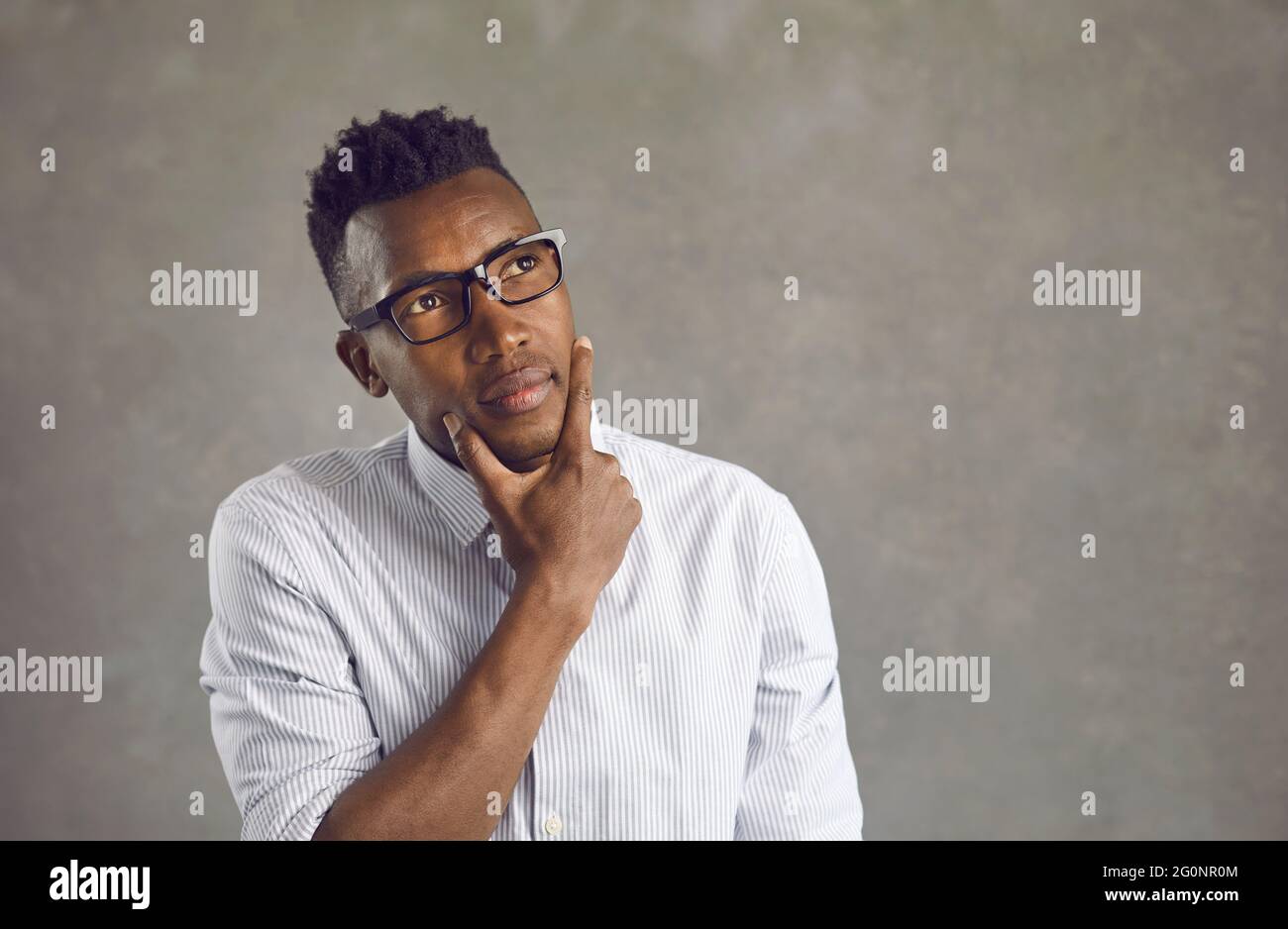 Jeune homme d'affaires afro-américain à lunettes profondément réfléchi à quelque chose Banque D'Images