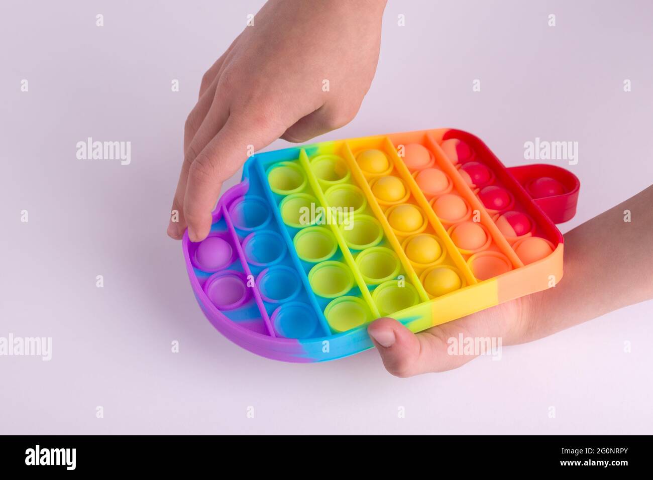 Les enfants jouent à la main avec le jouet de violon coloré arc-en-ciel pop il isolé sur le blanc. Banque D'Images