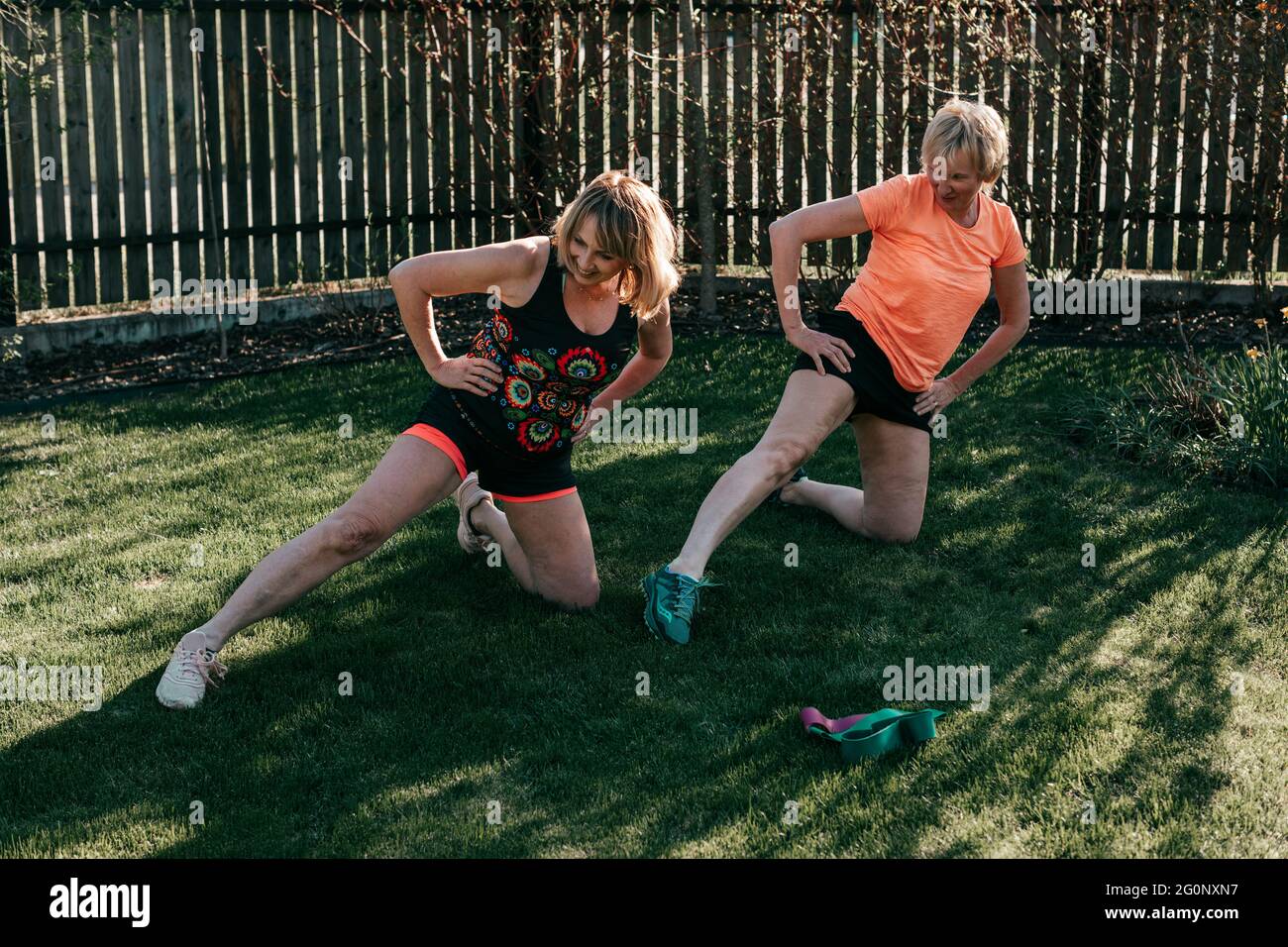 Les femmes âgées actives de 55-59 ans effectuent des exercices tout en étant allongées sur l'herbe le jour de l'été Banque D'Images