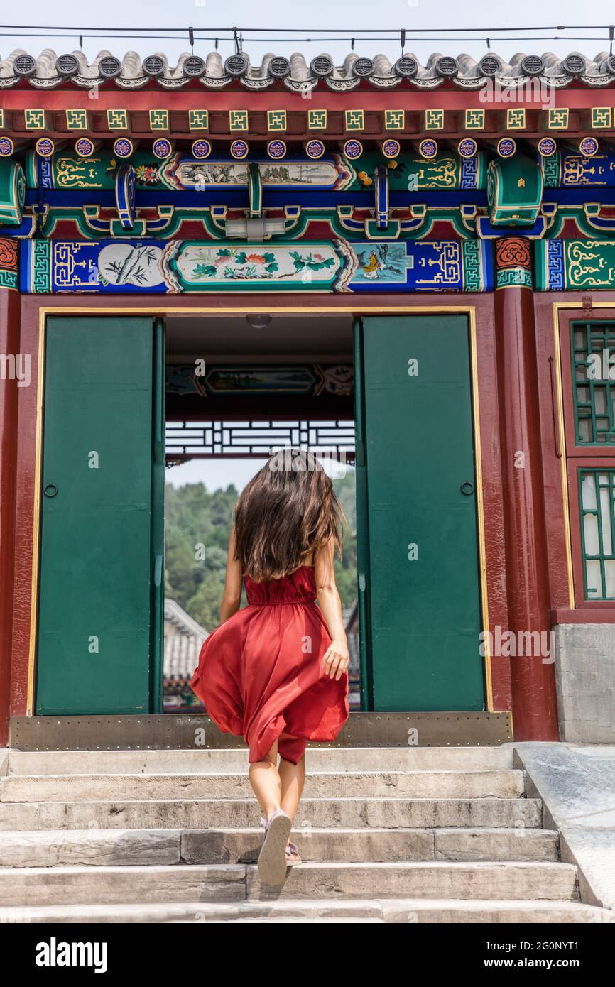 Femme élégante marchant à travers l'ancienne porte chinoise traditionnelle en bois à l'ancien temple impérial, voyage d'été en chine. Magnifique fille avec cheveux coulant et Banque D'Images