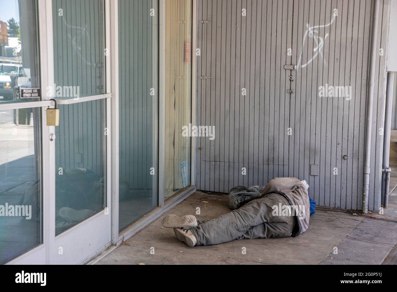Personne sans-abri dormant sur la glissdewalk à l'extérieur d'une vitrine vide sur Telegraph Ave. À Berkeley, Californie. Banque D'Images