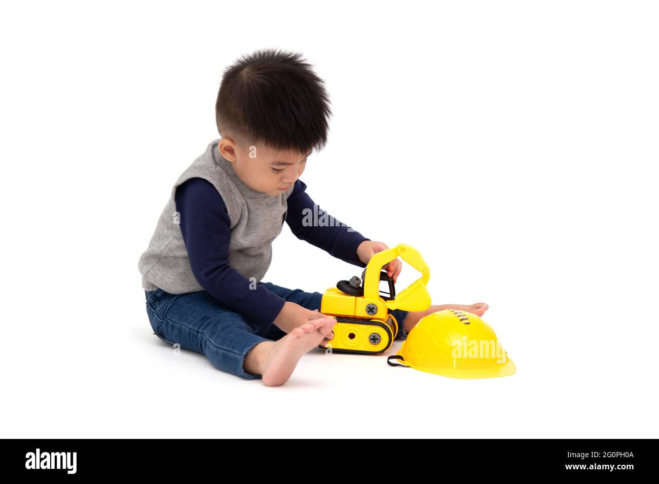 Portrait d'un adorable petit garçon asiatique assis sur le sol et jouant à la construction de jouet de voiture isolée sur fond blanc, 1 an 10 mois Banque D'Images