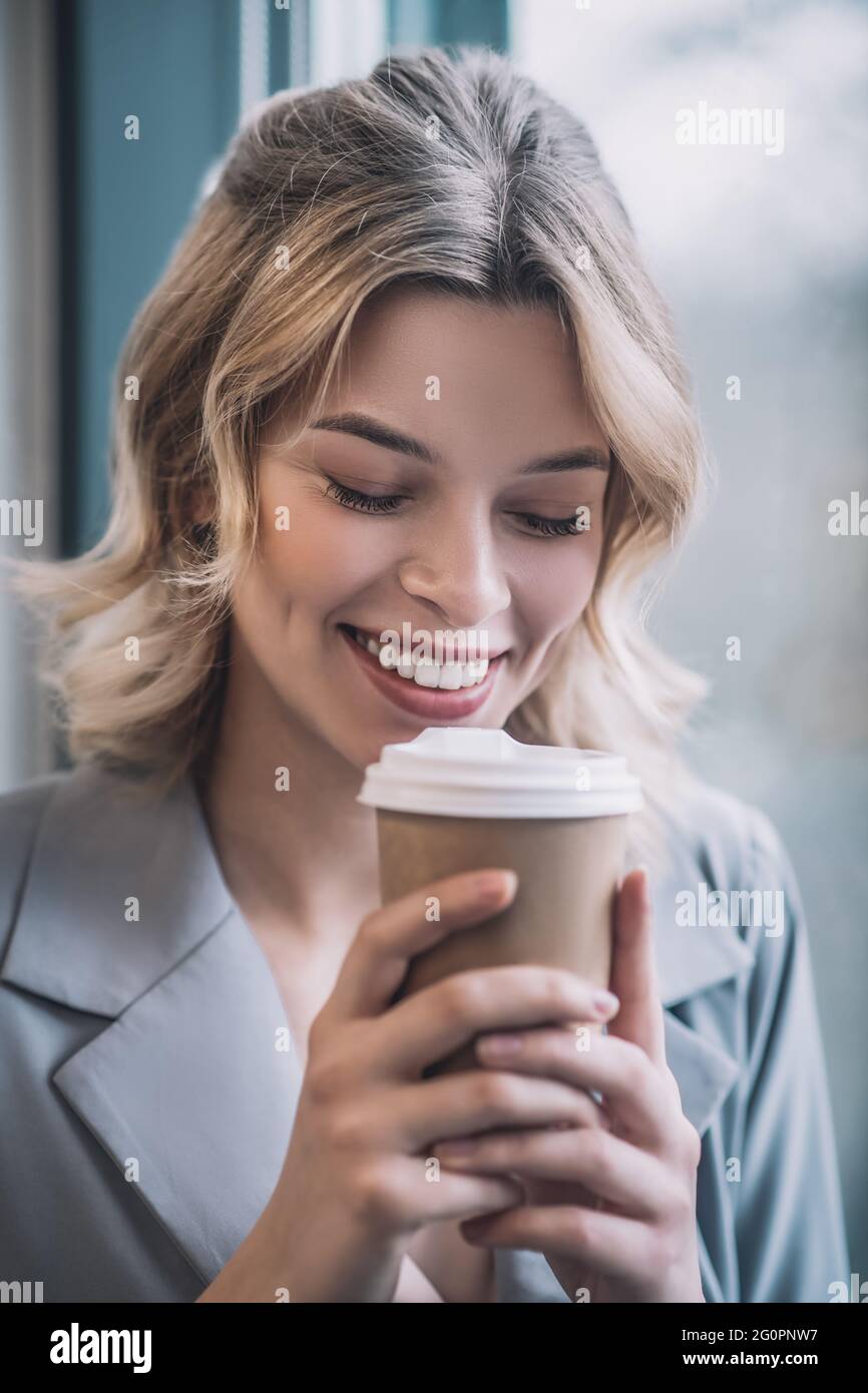 Femme souriante avec des paupières coudées apportant du café au visage Banque D'Images