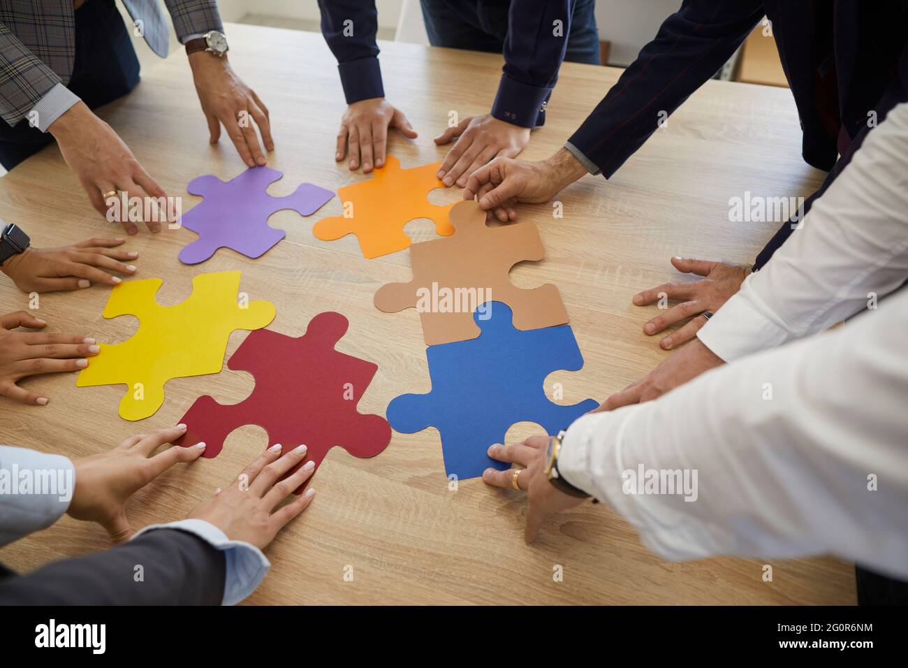 Équipe de professionnels de l'entreprise essayant d'assortir des pièces colorées d'un puzzle Banque D'Images