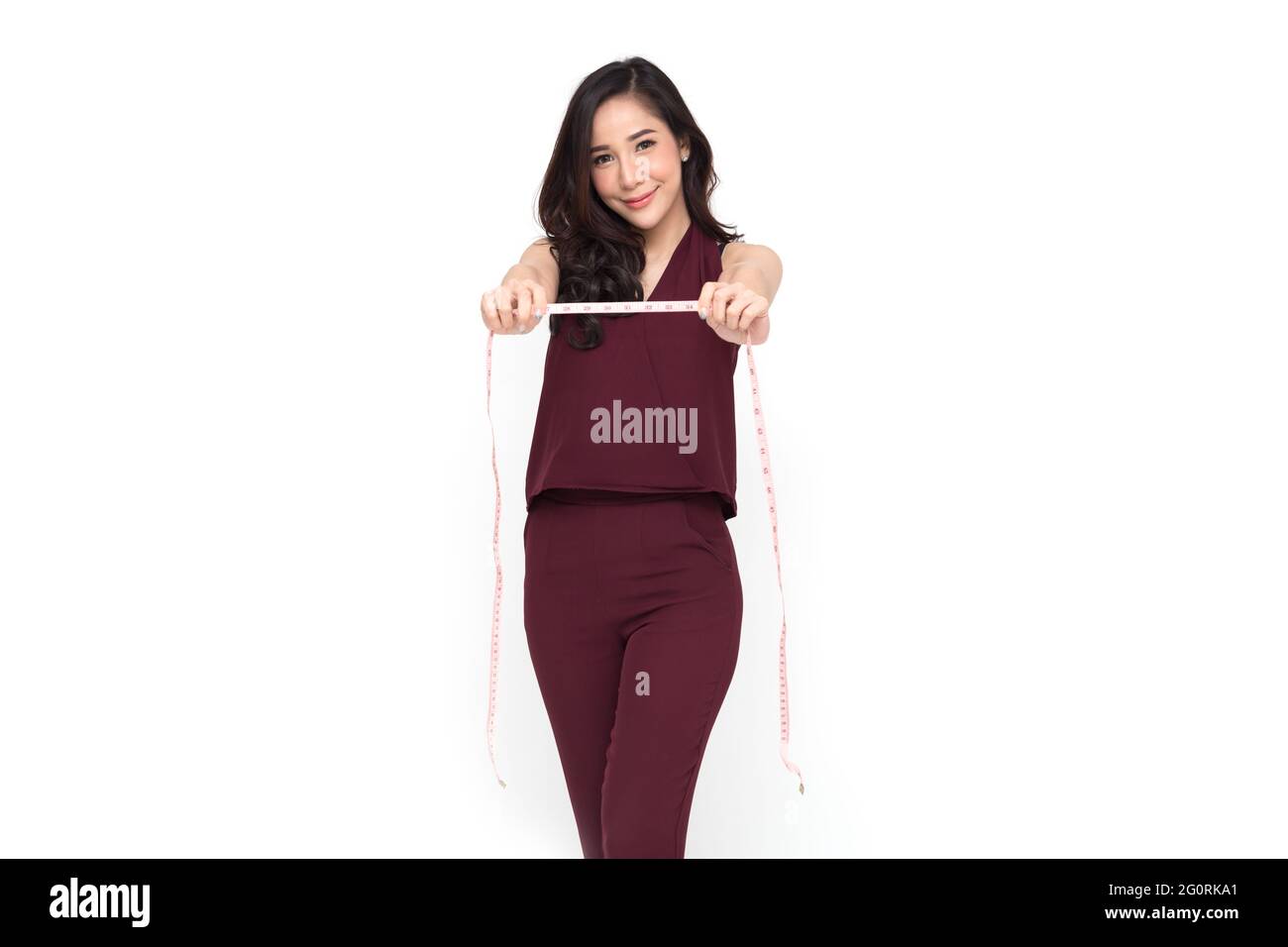 Portrait d'une femme de vêtements de créateurs de mode en robe rouge avec ruban à mesurer plus isolé sur fond blanc, modèle élégant femme asiatique Banque D'Images