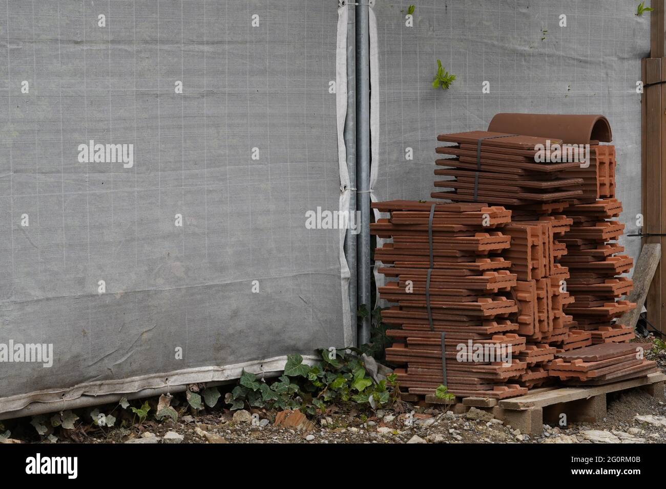 Tuiles de toiture groupées et placées sur une palette de bois sur un ...