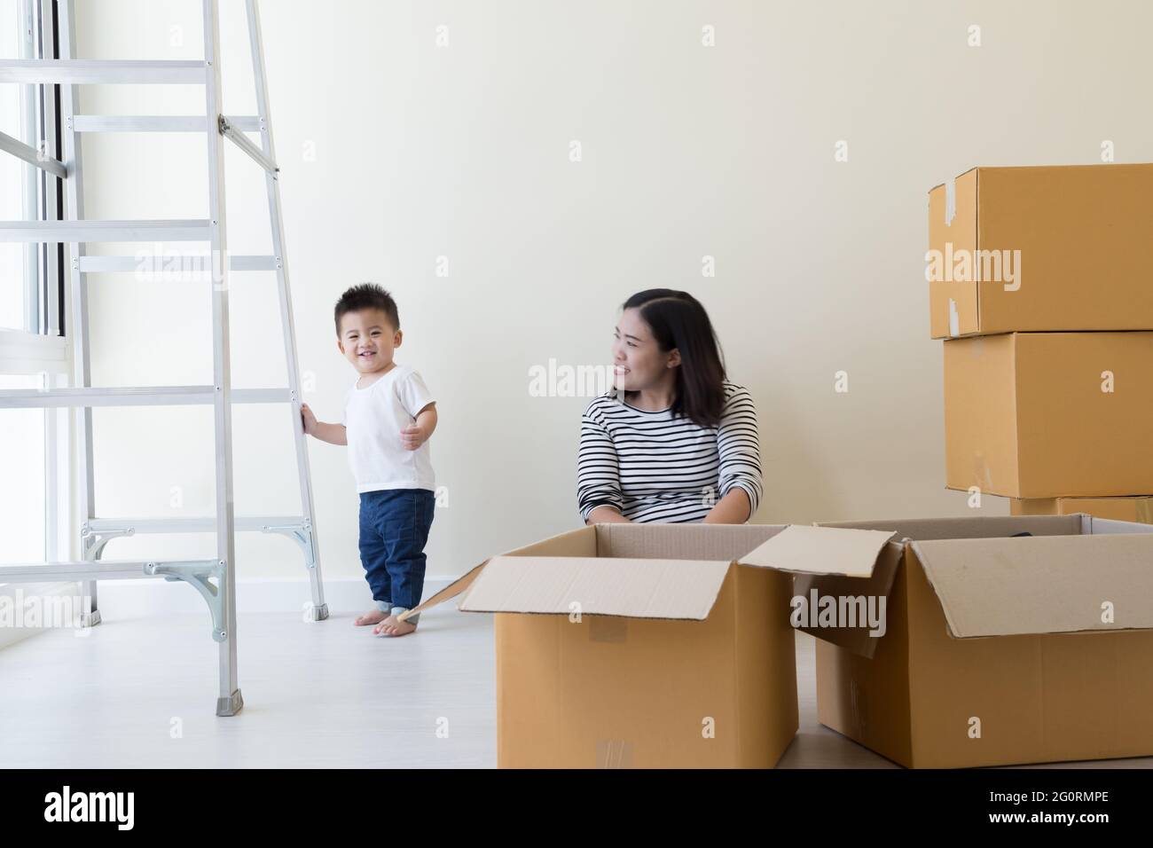 Mère asiatique et bébé garçon avec des boîtes en carton dans la nouvelle maison à la journée de déménagement, l'immobilier et le concept de famille à la maison Banque D'Images