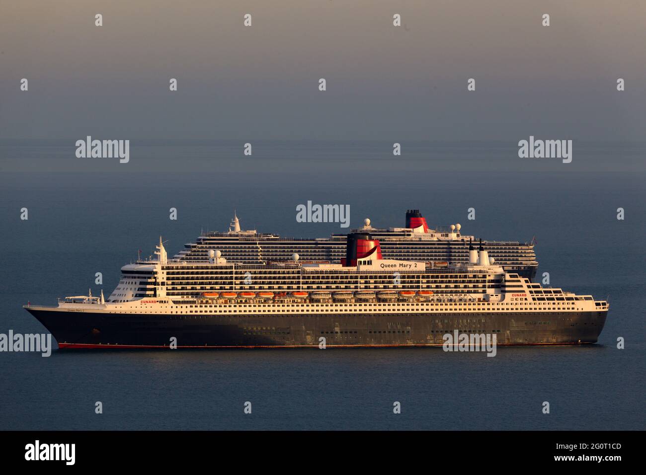 Deux Queens : les magnifiques bateaux de croisière Queen Mary 2 et Queen Victoria sont photographiés les uns les autres tout en étant ancrés au large de Torbay, Devon. Banque D'Images