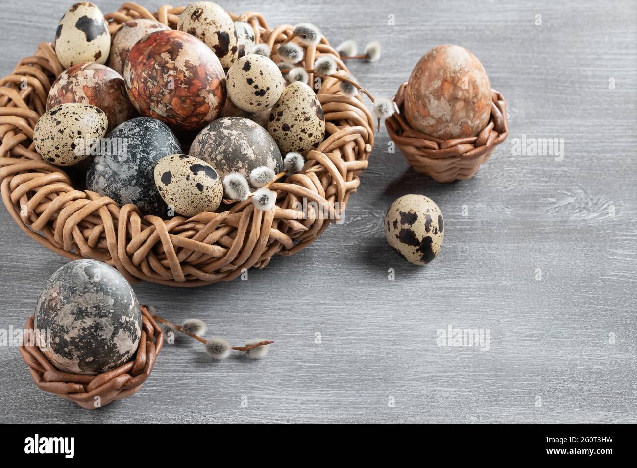 Composition Pâques - plusieurs œufs en marbre peints avec des teintures naturelles dans un nid et des paniers en osier, vue sur le dessus, espace copie. Banque D'Images