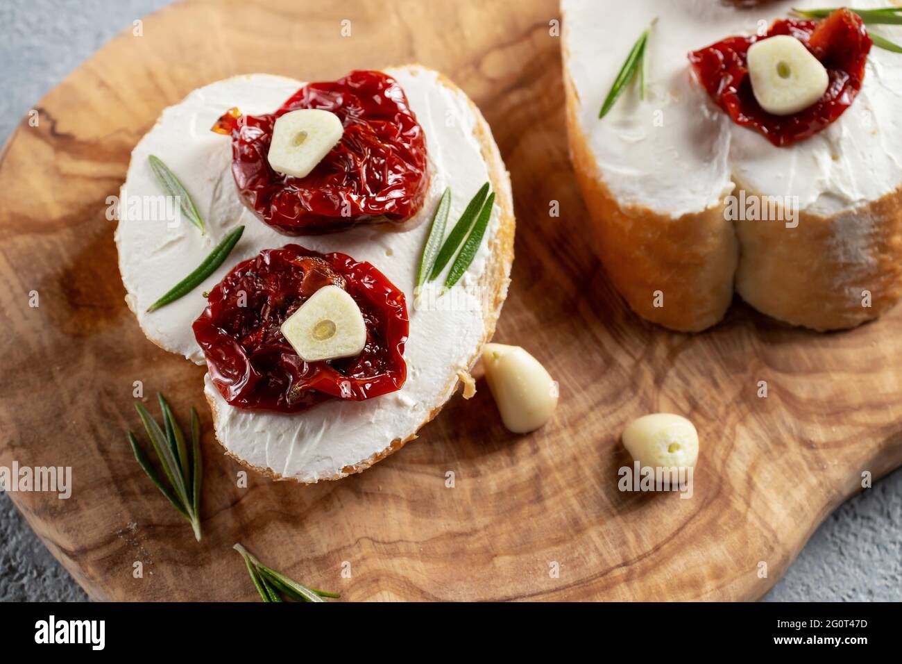 Sandwichs maison avec fromage à la crème et tomates séchées sur un plateau d'olives en bois - délicieux petit déjeuner sain, cuisine italienne. Banque D'Images