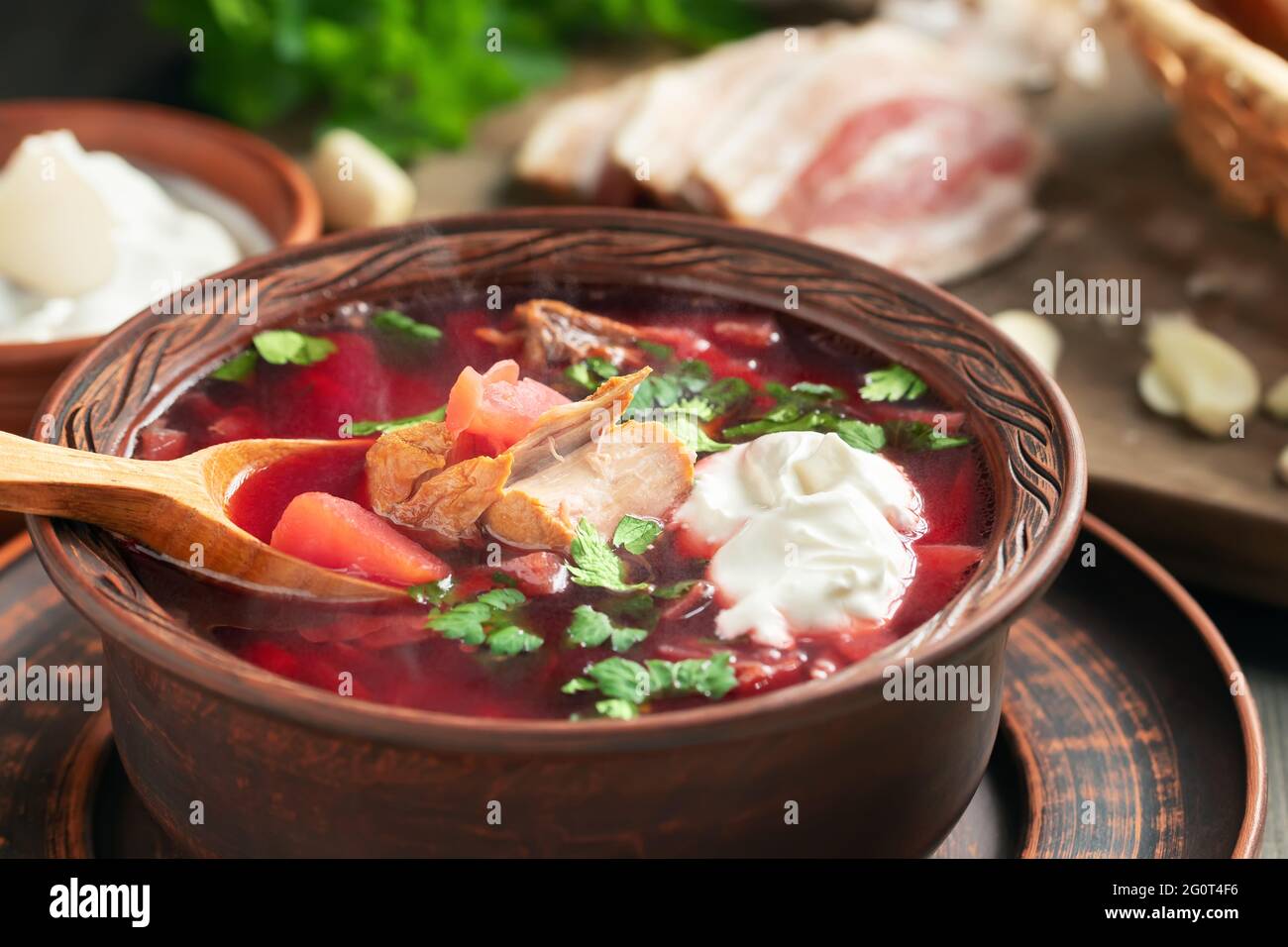 Le borscht fraîchement cuit est un plat traditionnel de cuisine russe et ukrainienne composé de plats en faïence avec bacon, pain, crème sure et ail. Banque D'Images