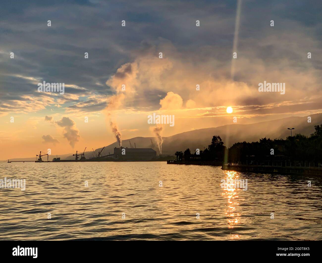 Les gens pêchant avec un crochet au bord de la mer, la fumée polluante sortant de la cheminée de l'usine en arrière-plan, 2 juin 2021, golfe Kocaeli Banque D'Images