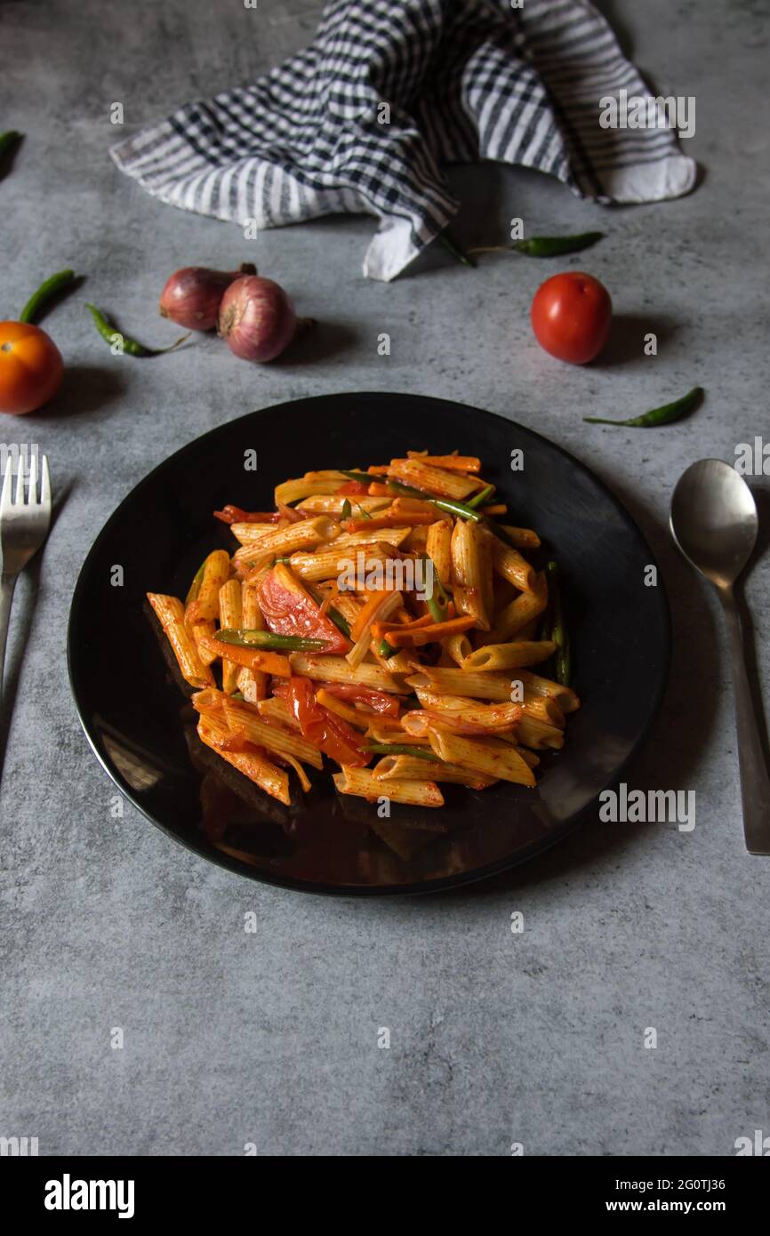 Pâtes alimentaires italiennes avec sauce tomate sur une assiette noire. Banque D'Images
