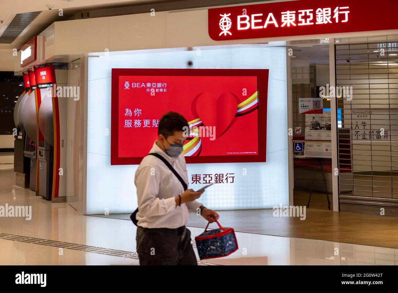 Hong Kong, Chine. 25 mars 2021. Un homme portant un masque passe devant la branche de la Banque d'Asie de l'est (BEA) et le logo vu à Hong Kong. Crédit: Budrul Chukrut/SOPA Images/ZUMA Wire/Alay Live News Banque D'Images