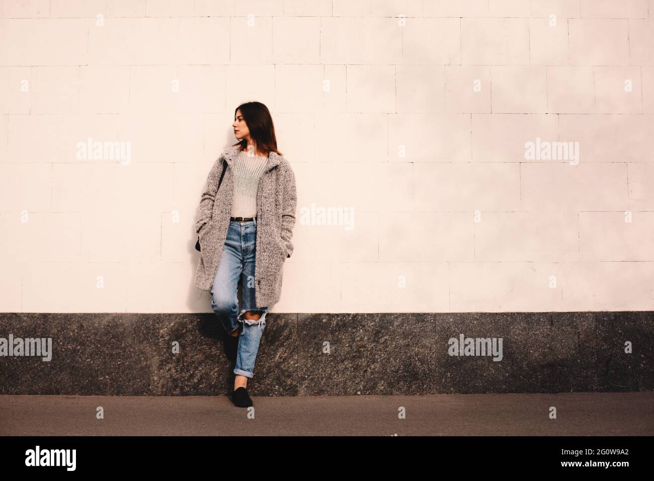 Jeune femme non binaire debout contre le mur dans la ville Banque D'Images