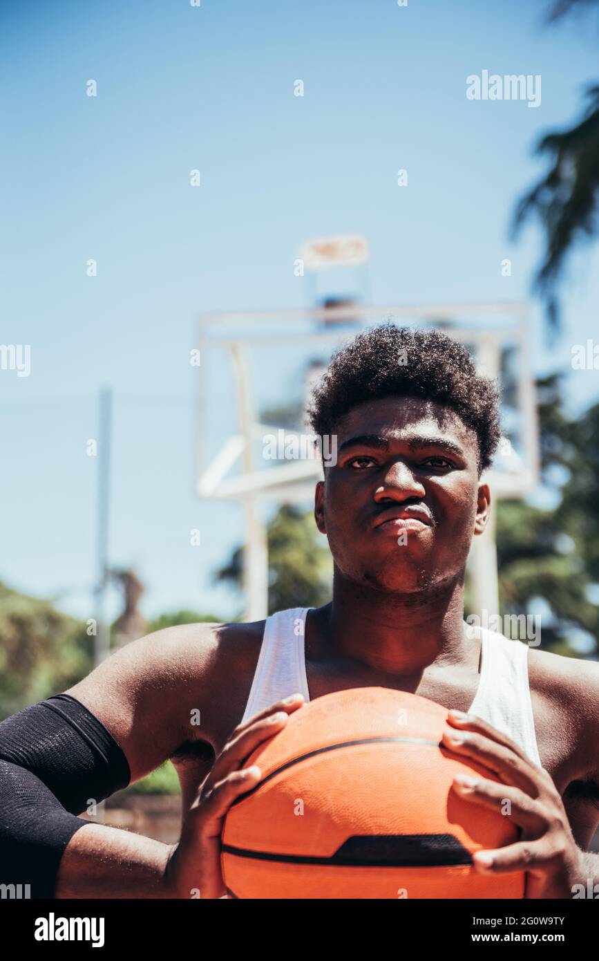 Portrait d'un garçon afro noir furieux avec un look provocateur en serrant le basket-ball avec ses mains. Prêt à jouer. Banque D'Images