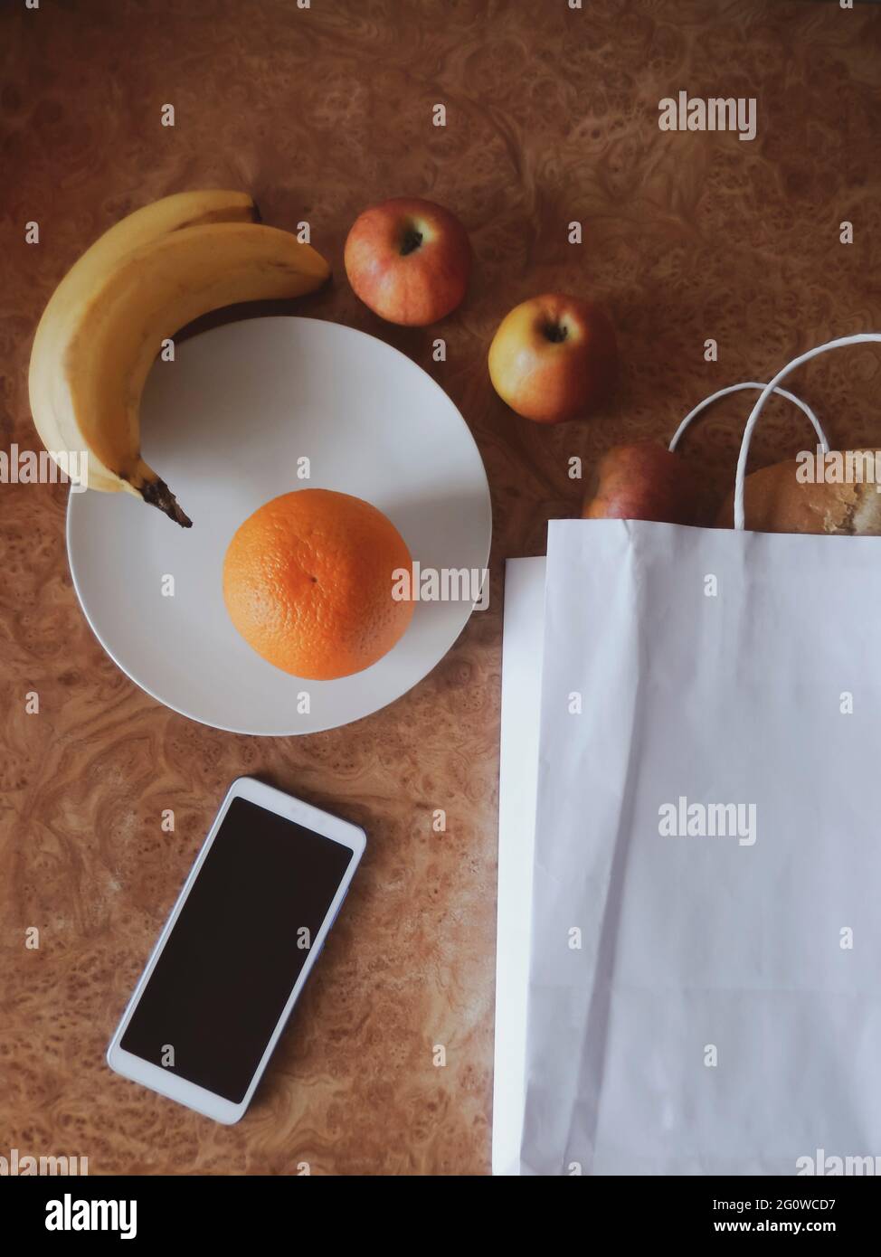 à la cuisine: sac de papier, fruits, pain, téléphone, assiette. concept de shopping Banque D'Images