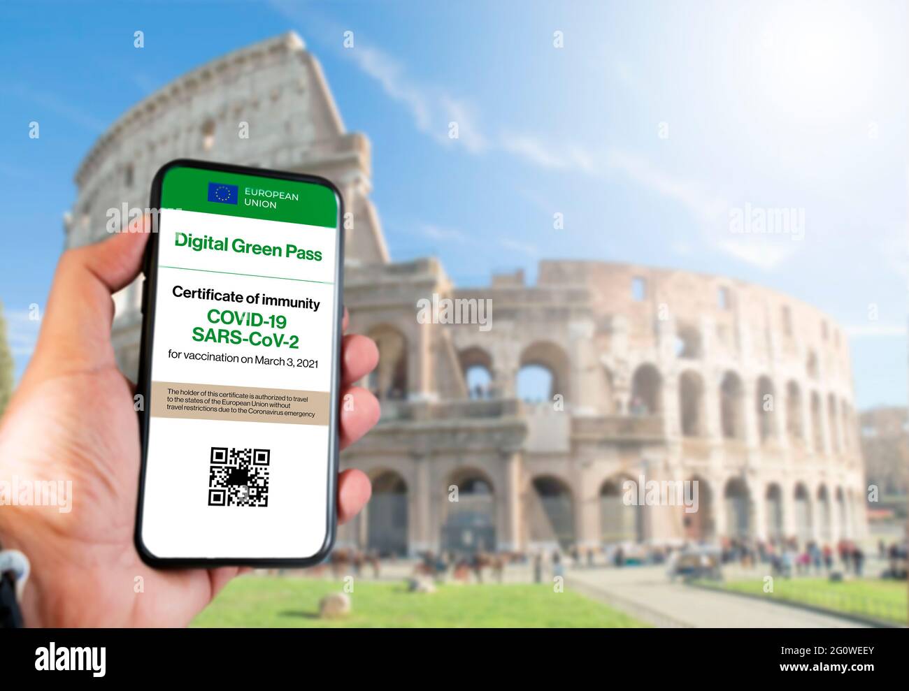 Le passe numérique vert de l'Union européenne avec le code QR sur l'écran d'un mobile tenu par une main avec un Colisée flou en arrière-plan. IMMUN Banque D'Images