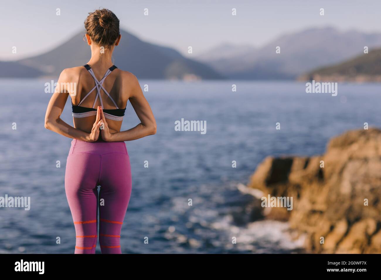 Belle jeune femme faisant la méditation sur la falaise près de la mer. Concept de yoga et d'exercice dans la nature. Banque D'Images