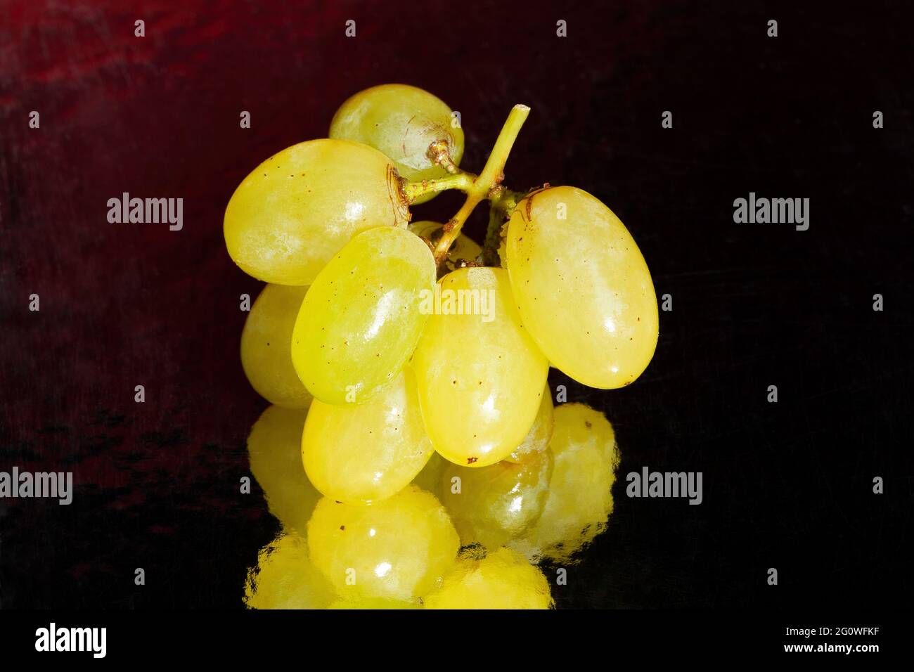 raisin blanc sur fond réfléchissant noir Banque D'Images