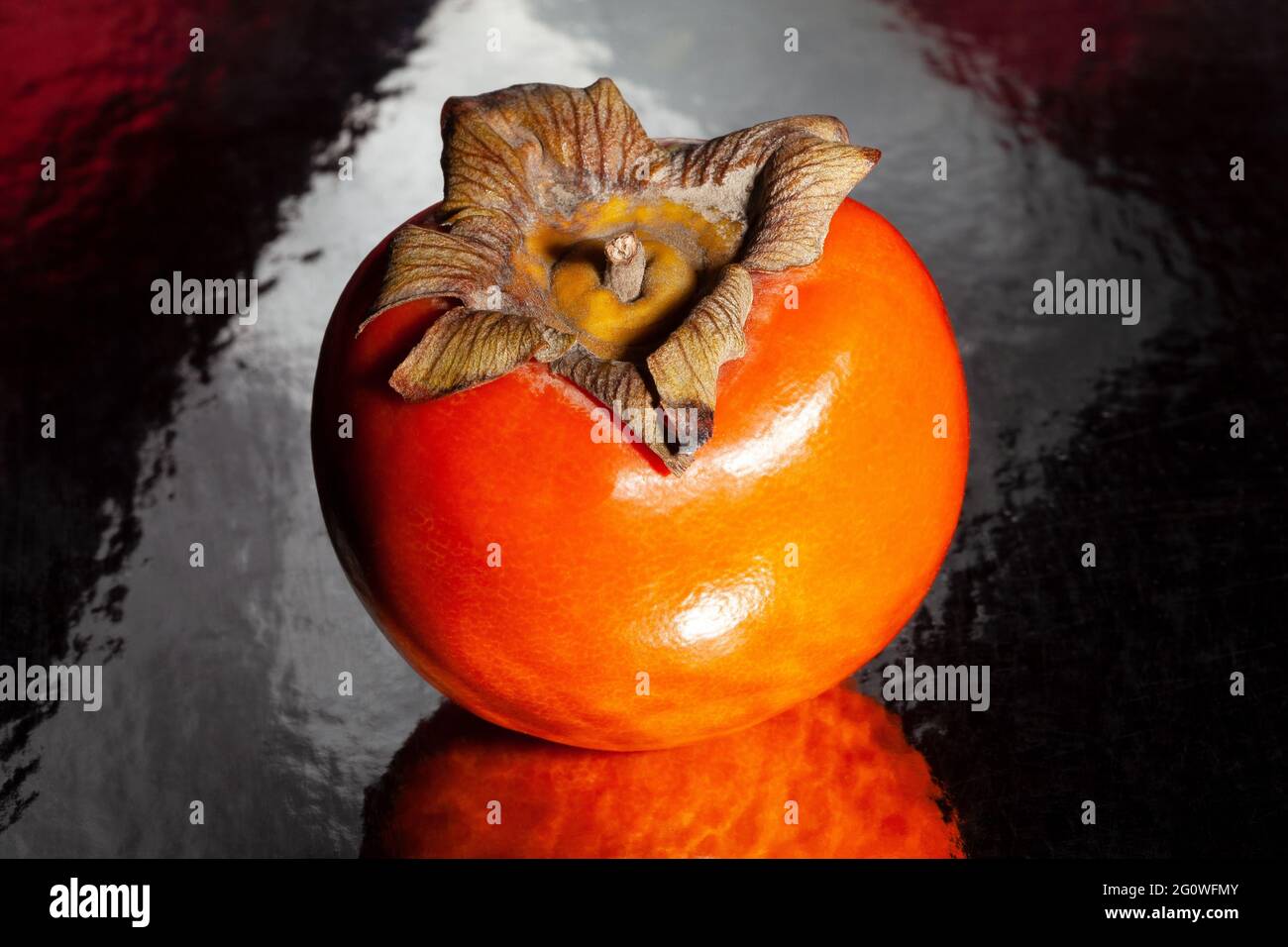 persimmon sur fond réfléchissant noir Banque D'Images