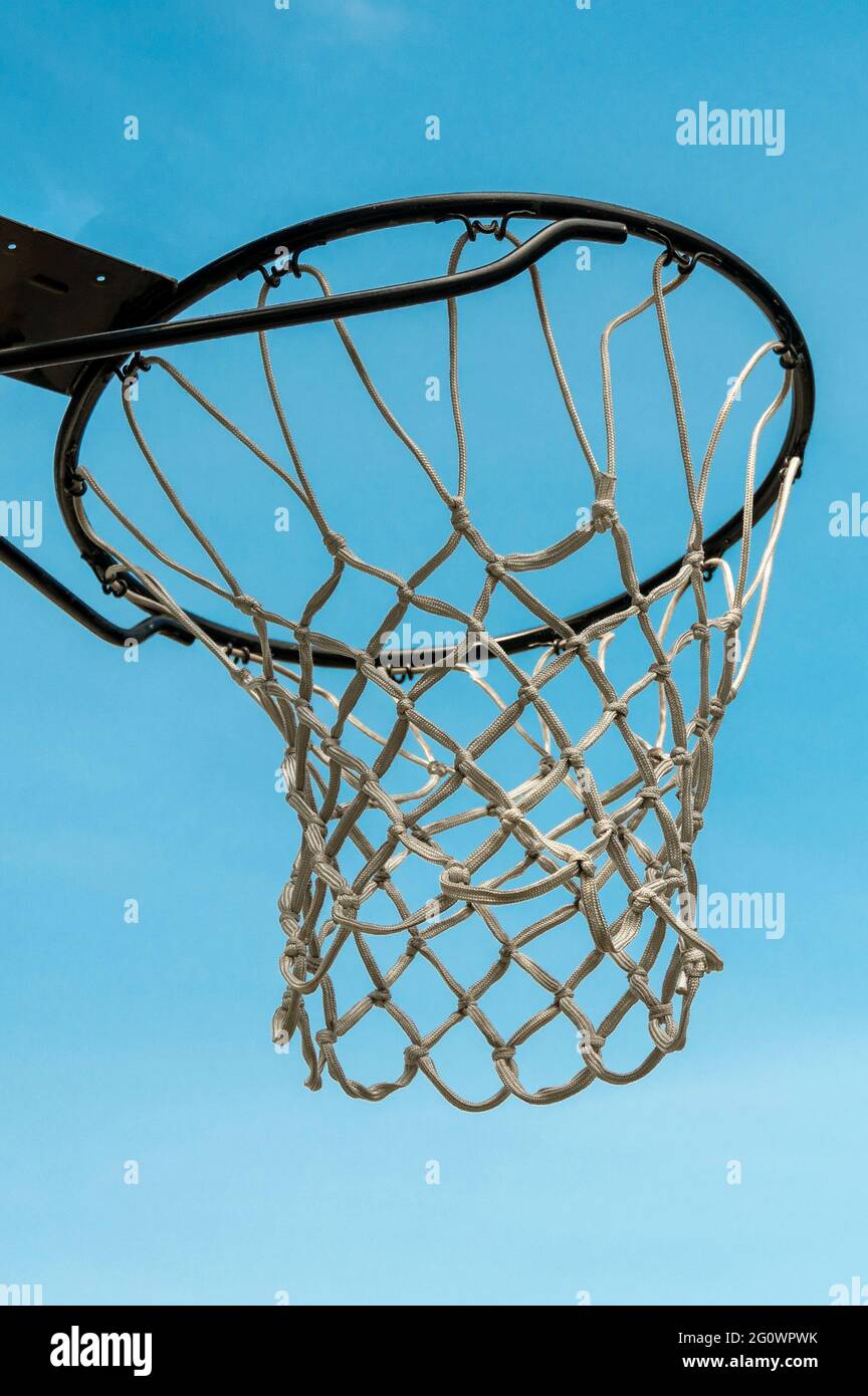 Un panier de basket-ball est suspendu sur un grand panier noir contre un ciel bleu Banque D'Images