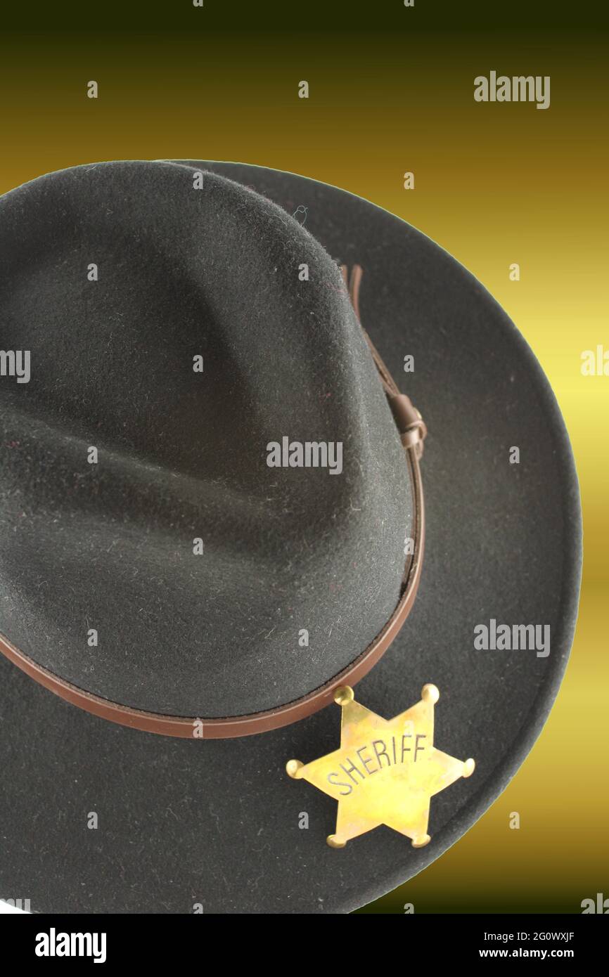 Chapeau de cow-boy noir avec badge Sheriffs sur fond doré avec espace de copie Banque D'Images