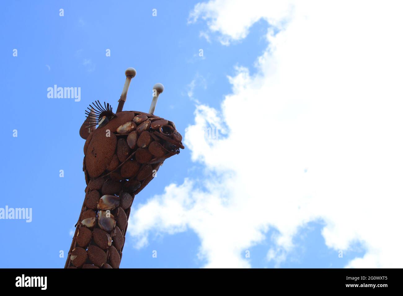 Sculpture métallique tête et cou girafe avec ciel bleu et nuages blancs. Avec espace de copie Banque D'Images