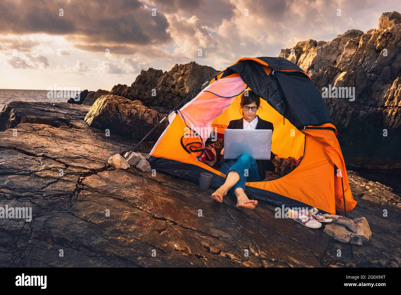 Femme assise dans la tente et travaillant sur ordinateur. Femme d'affaires travaillant de la plage. Concept de travail à distance. Travail et voyages de freelance o Banque D'Images